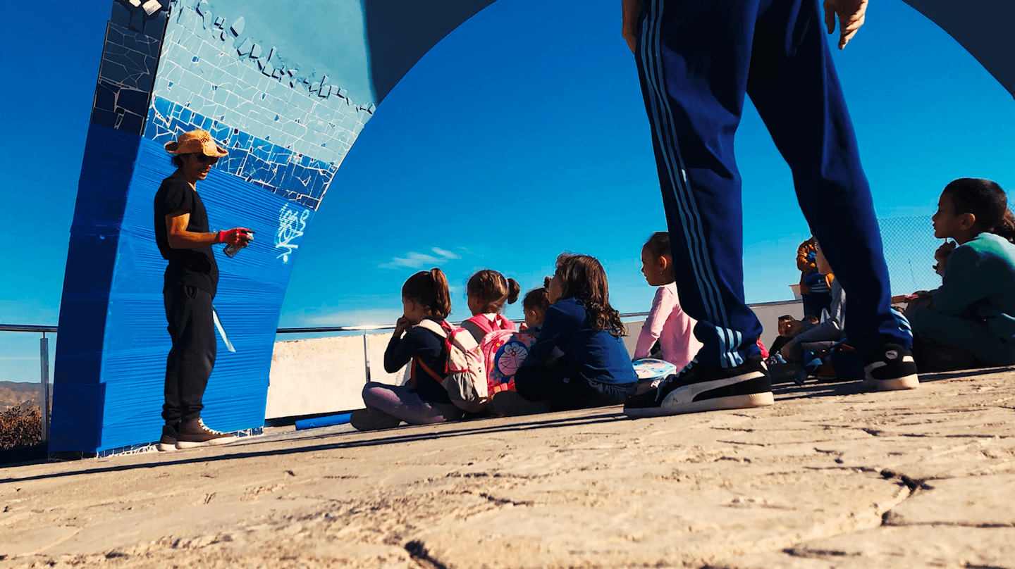 School group participating in an outdoor art workshop with local artist Nohek, creating collaborative artwork