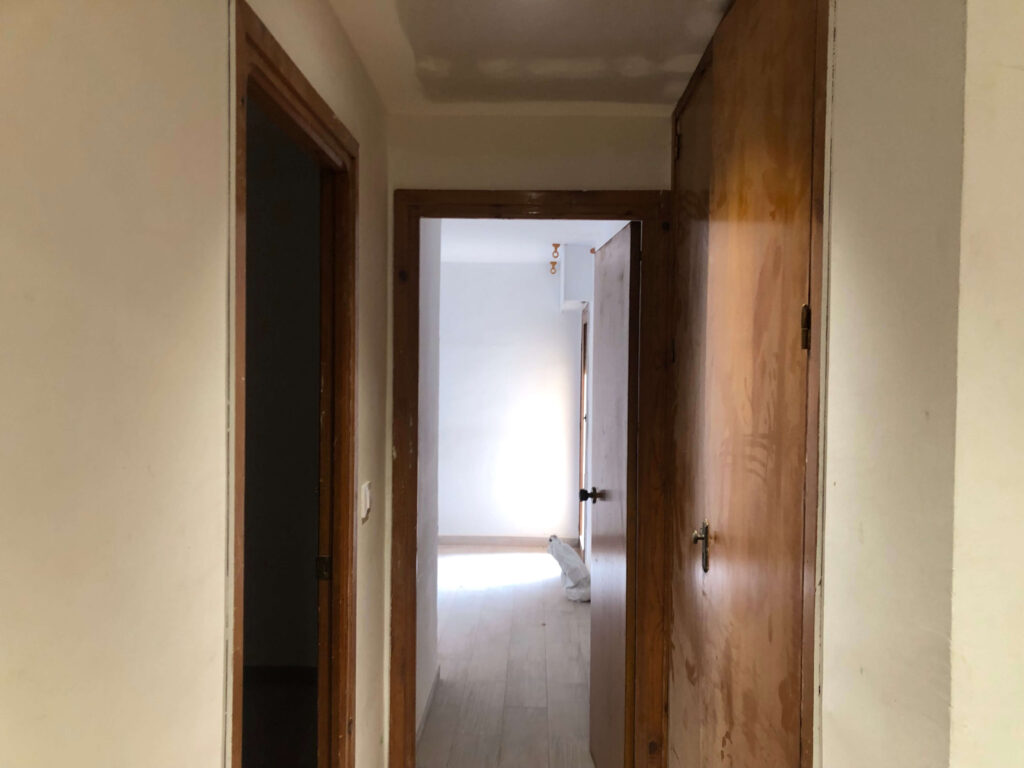 Image of a flat prepped and ready for painting:
"Flat prepped for painting with walls patched and smoothed, painter's tape applied along the edges and trim, and furniture covered with protective sheets, ensuring a clean and organized workspace."